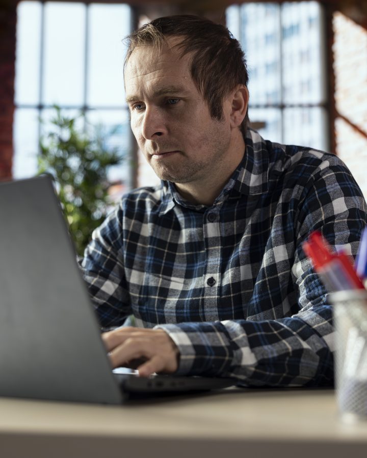 Skupiony programista przy laptopie w biurze typu loft